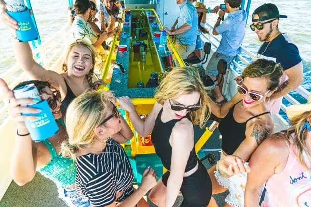 A group of people on a boat, having drinks and enjoying a fun-filled Paddle Pub experience