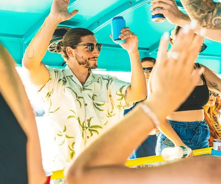 A guest raising a can as the group cheers around him under the canopy