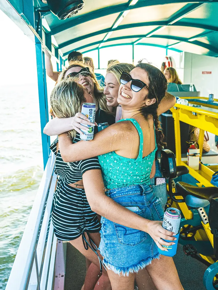 Two friends laughing together on deck, drinks in hand