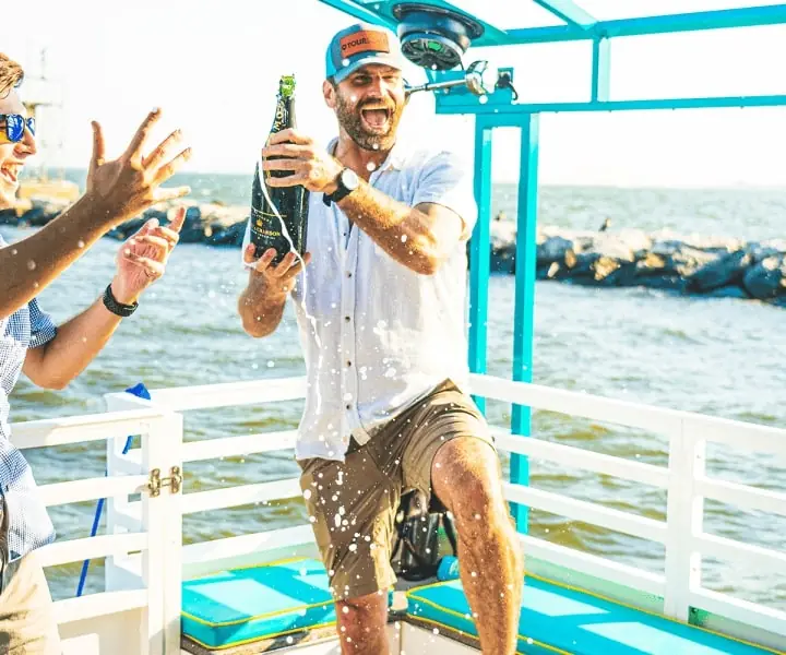 A guest spraying champagne on the deck of a Paddle Pub boat