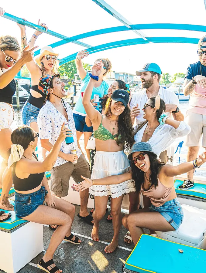 Group of friends enjoying a boat party on a sunny day, wearing casual summer clothing and accessories